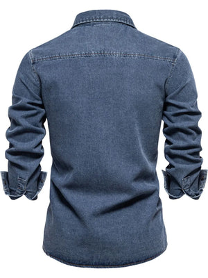 Light blue denim utility shirt with buttoned cuffs and a zip pocket detail.