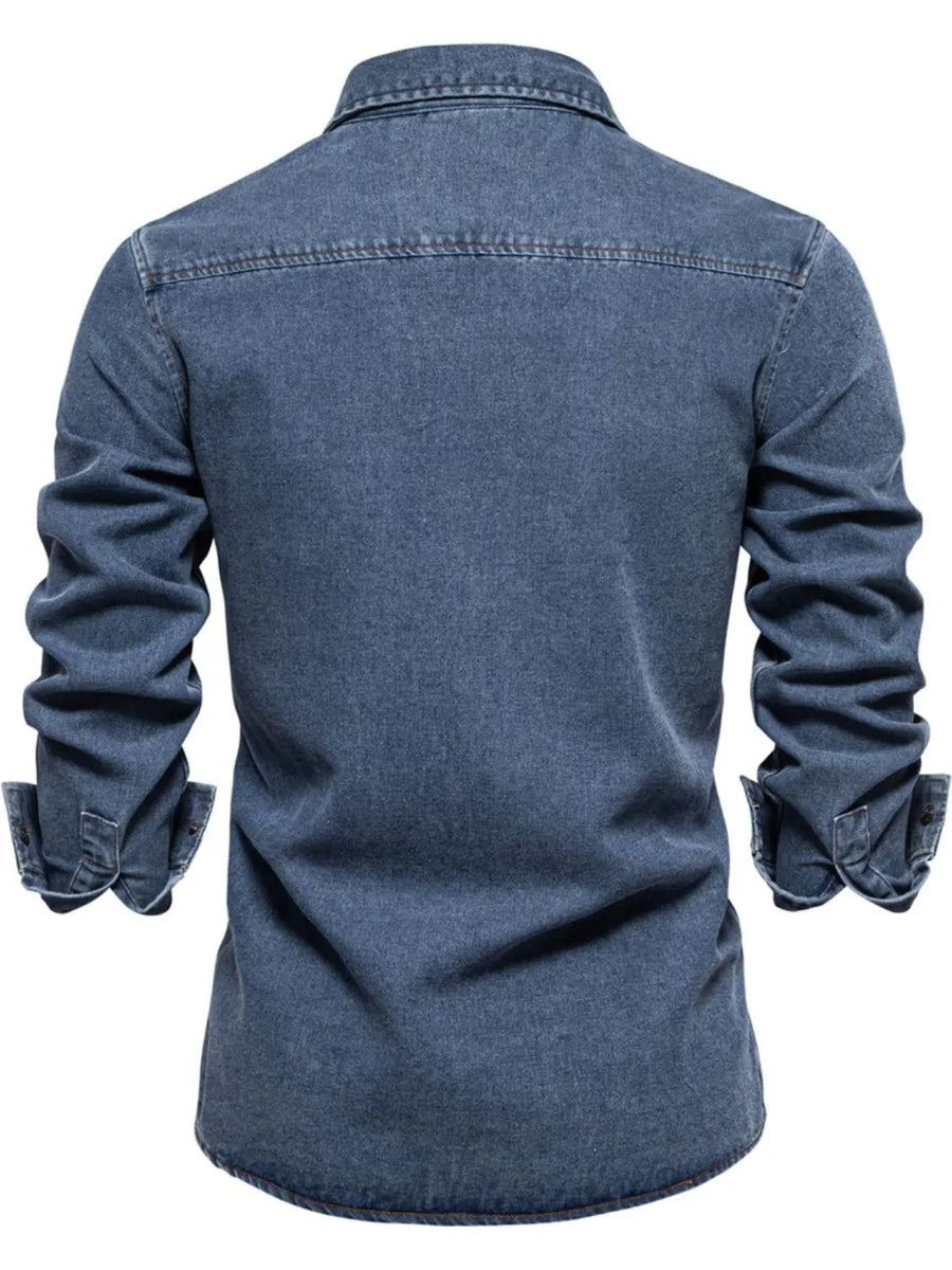 Light blue denim utility shirt with buttoned cuffs and a zip pocket detail.