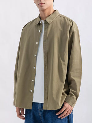 Men's long sleeve button-up shirt in olive green, styled casually over a white tee.