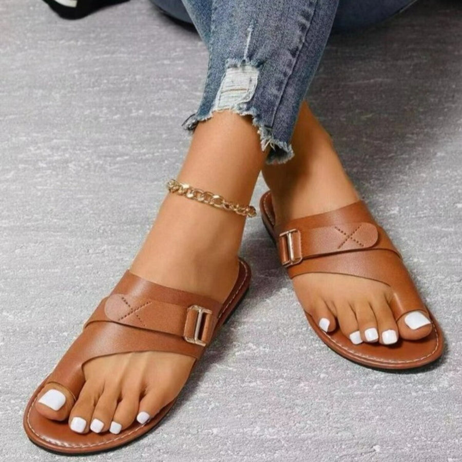 Brown toe ring sandals with buckle detail and crisscross straps.