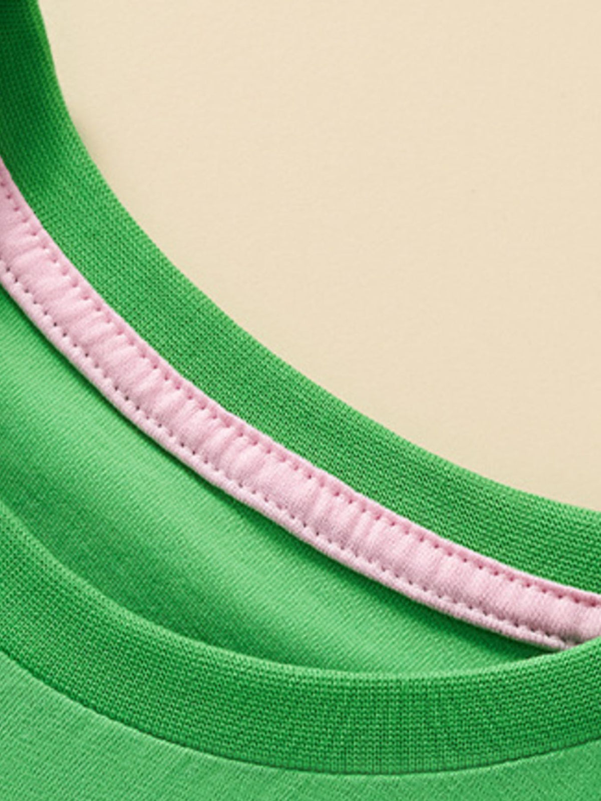 Green cotton t-shirt with pink trim detail on the neckline.