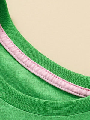 Green cotton t-shirt with pink trim detail on the neckline.
