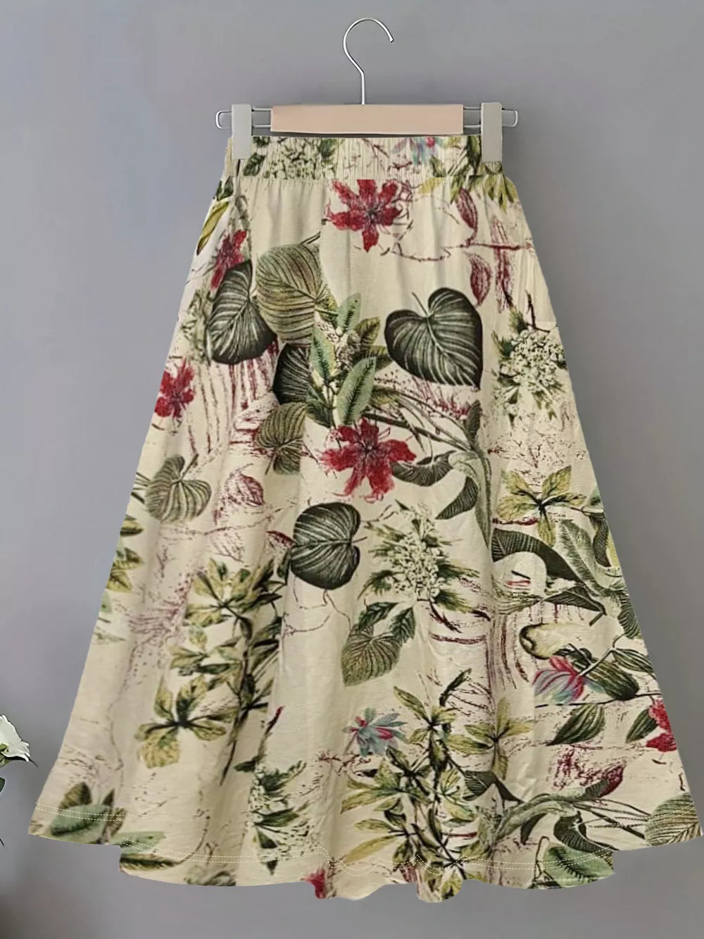 A-line skirt with elastic waist and botanical print in cream with red and green flowers and leaves.