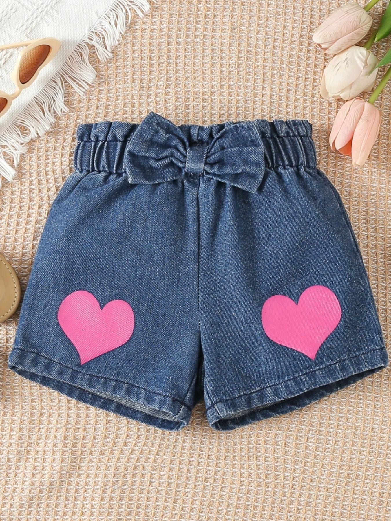 Denim shorts with pink hearts and a bow detail.