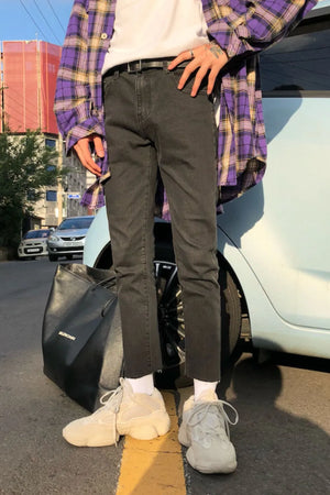 Dark washed denim slim-fit jeans with raw hem, styled casually.