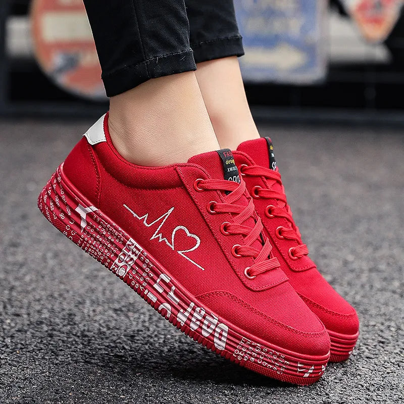 Red canvas sneakers with white heartbeat and heart graphic, and text print on sole.