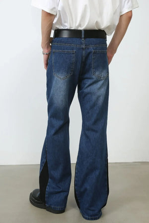 Medium wash bootcut denim trousers with black contrast panels and flared leg.