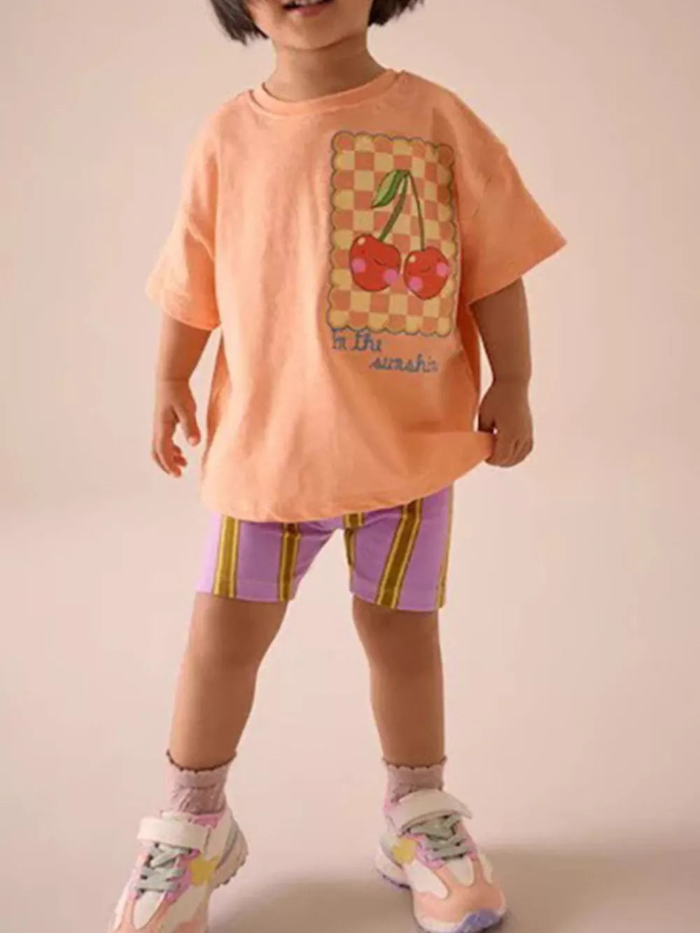 Toddler peach t-shirt with cherry graphic and checkered detail.