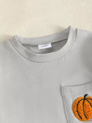 Baby grey t-shirt with orange pumpkin appliqué on chest pocket.