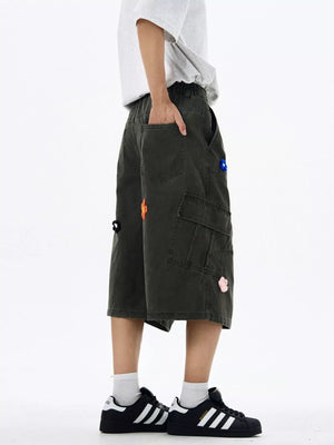 Dark gray cotton cargo shorts with floral appliques and wide legs.