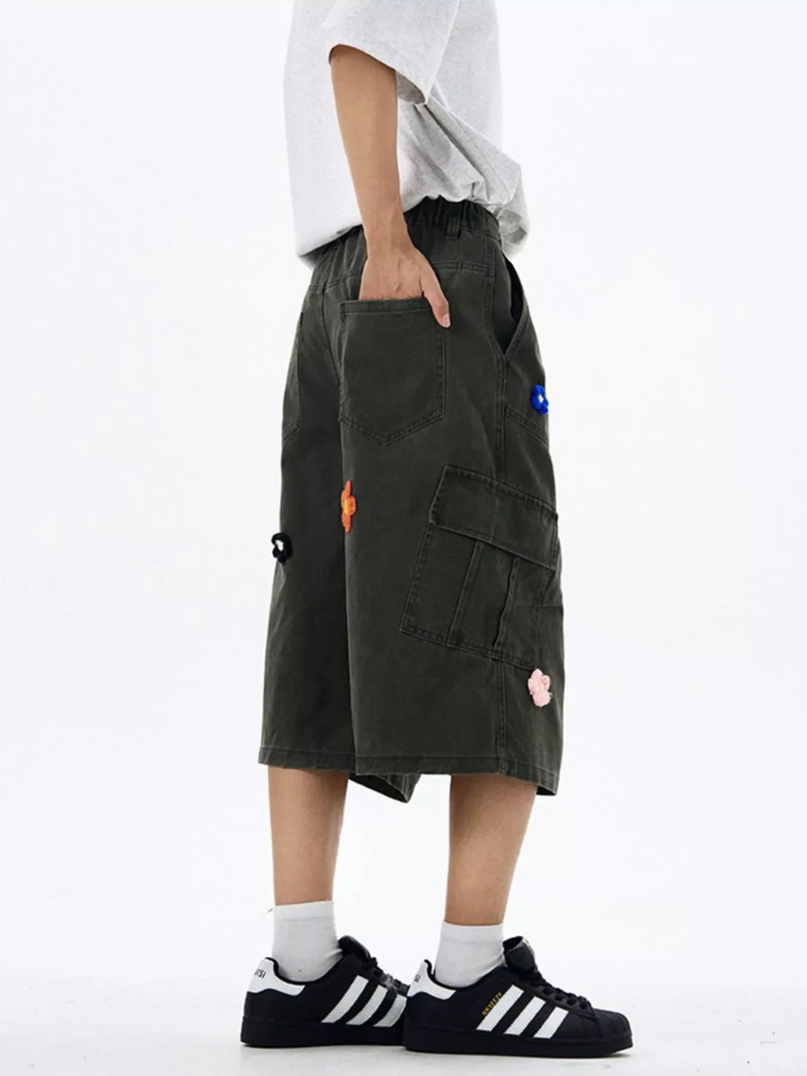 Dark gray cotton cargo shorts with floral appliques and wide legs.