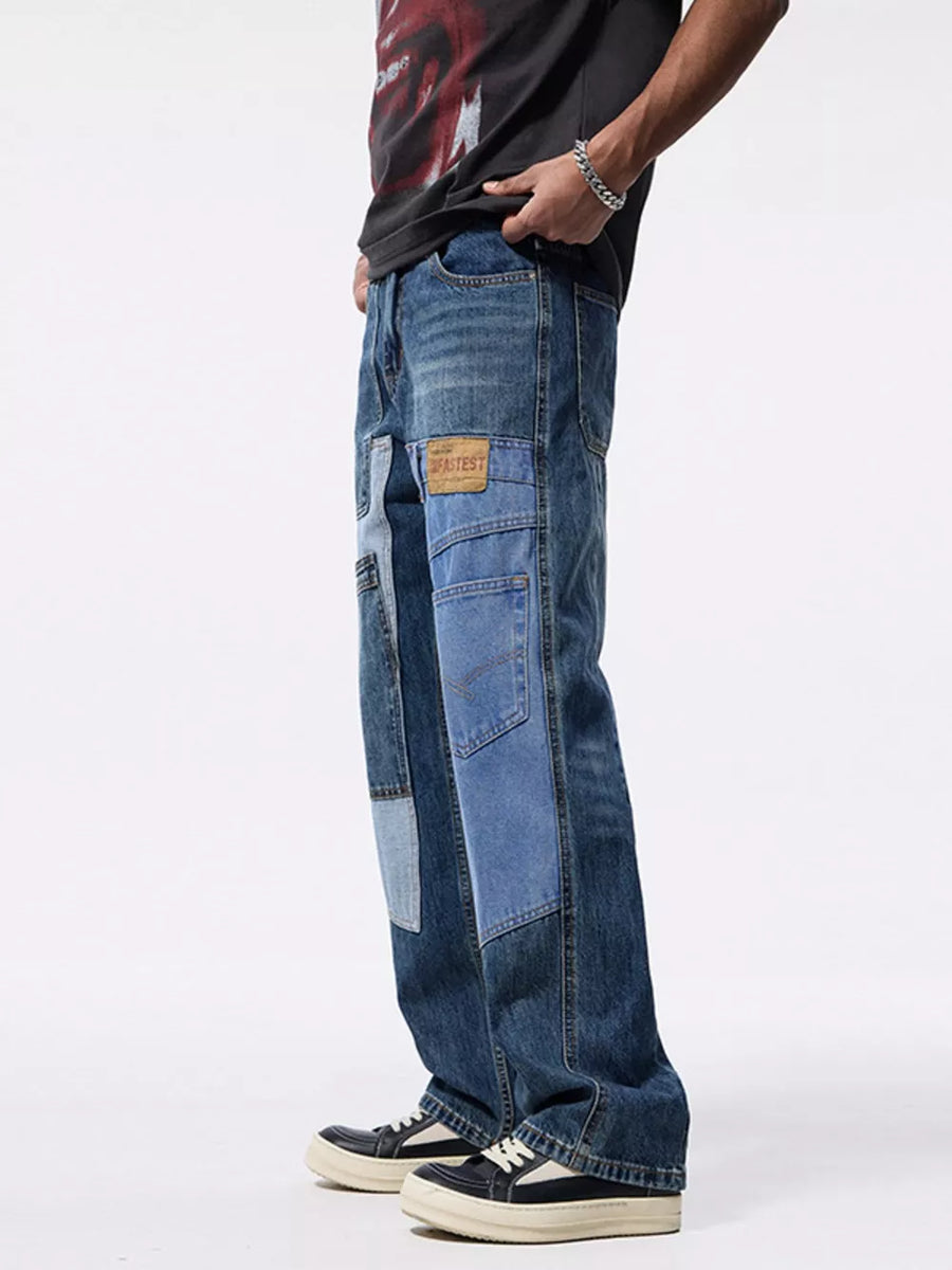 Relaxed fit patchwork jeans in blue denim with distressed details and a leather patch.