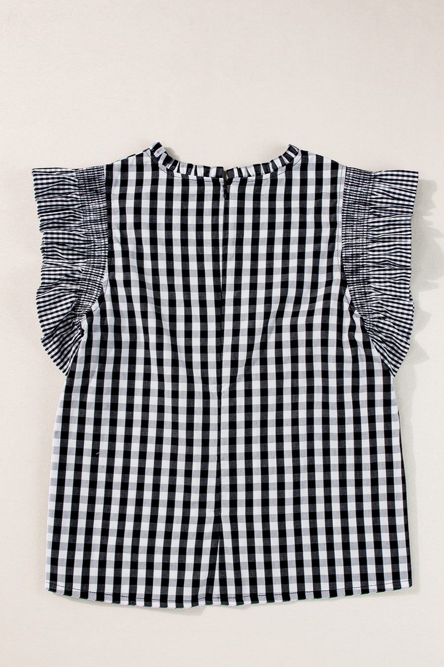Black gingham blouse with mock neck and ruffled cap sleeves.