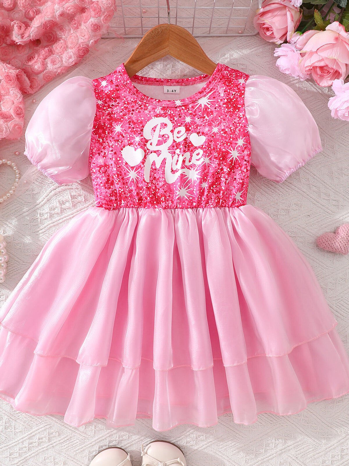 Pink sequin baby dress with puff sleeves and "Be Mine" graphic, tiered skirt.