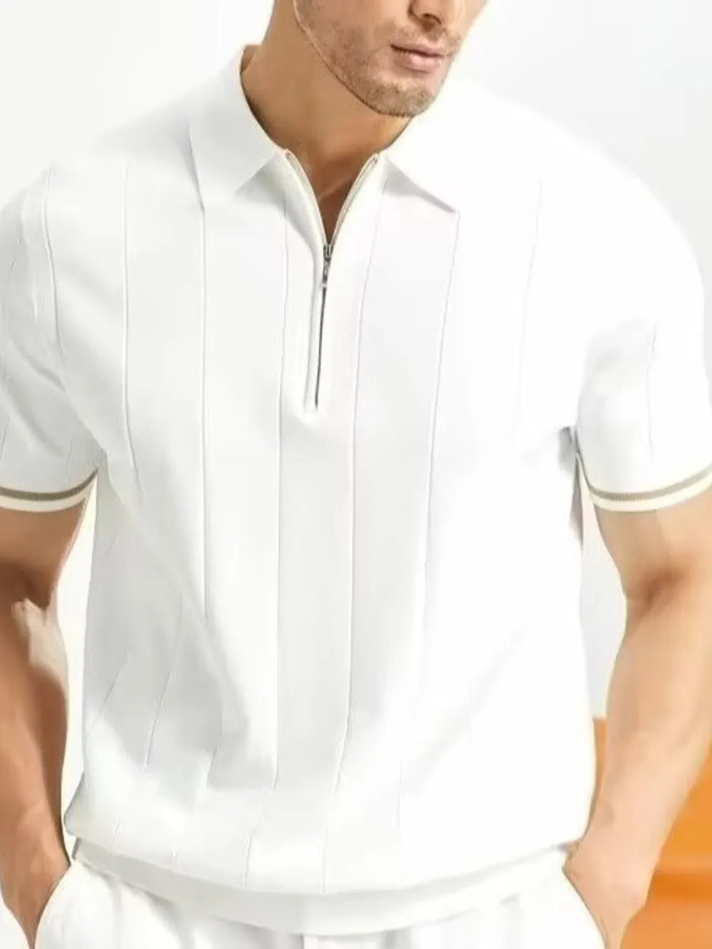 White cotton quarter-zip polo shirt with vertical seam details and striped cuffs.