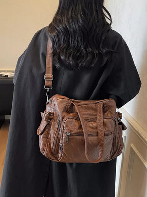 Brown faux leather crossbody bag with multiple zippered pockets and adjustable strap.