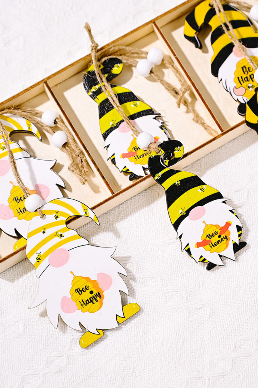 Whimsical bee gnome ornaments in yellow and black stripes with bee designs and text.