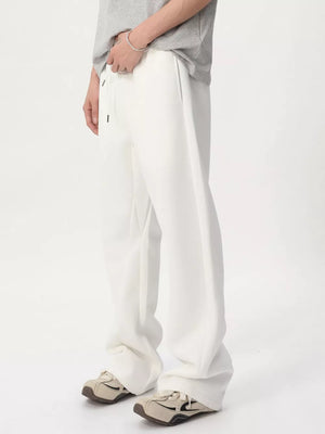 White relaxed fit sweatpants with adjustable drawstring waist and wide leg, shown on a man.
