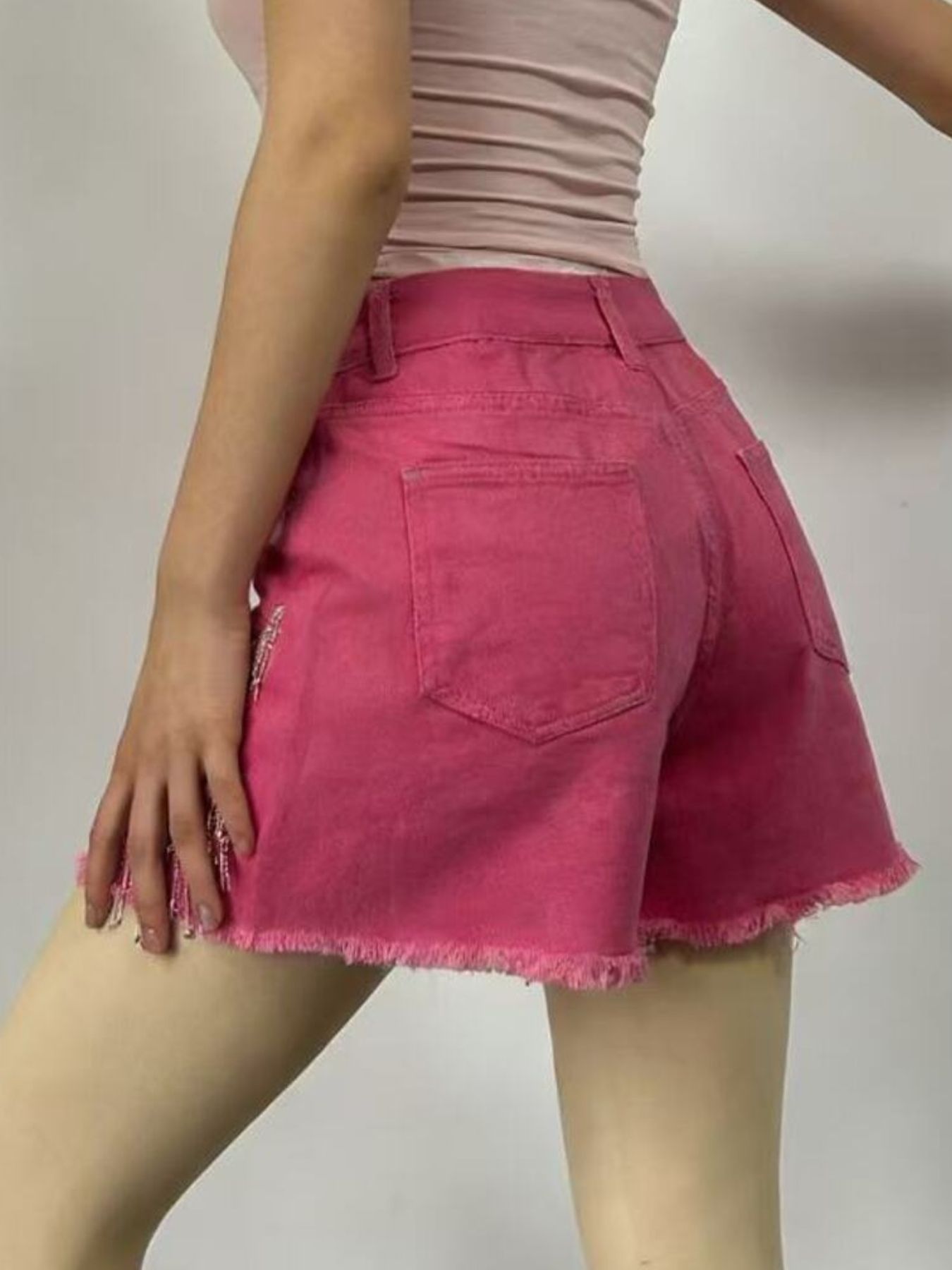 Fuchsia pink denim shorts with rhinestone chain detail and frayed hem.