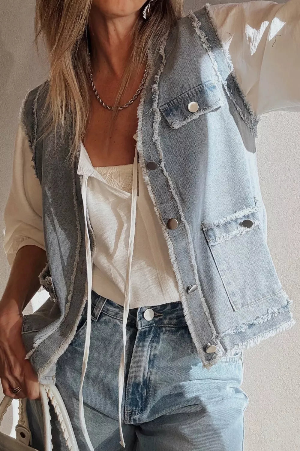 Light wash denim vest with frayed edges, button-down front, and chest pockets.