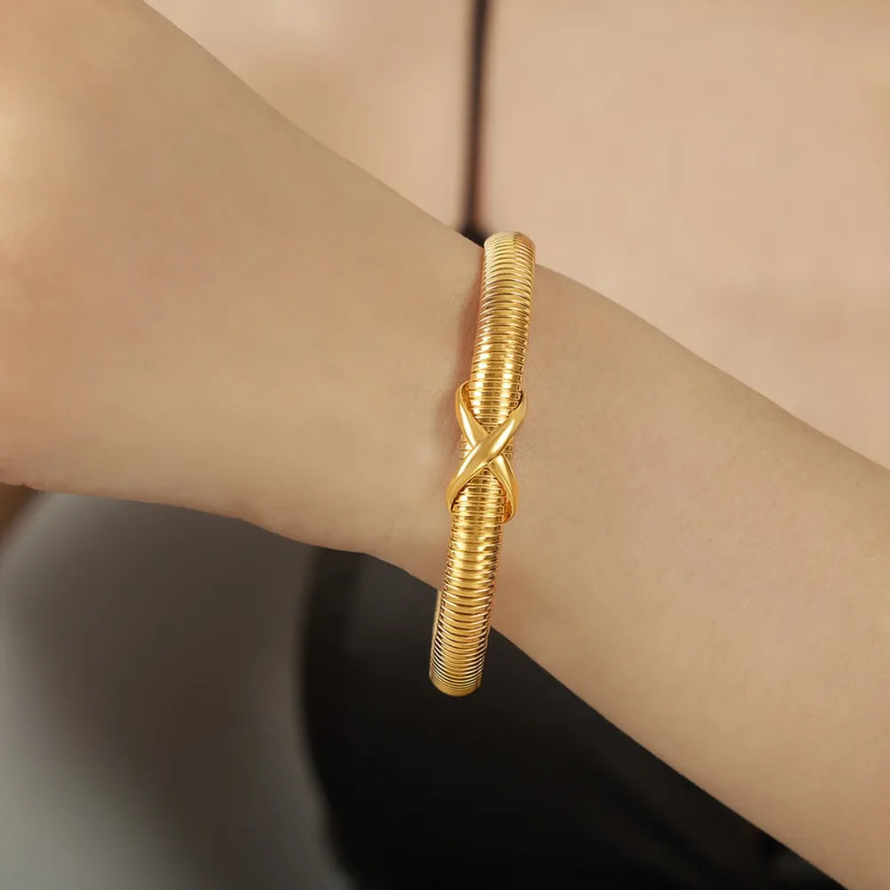 Gold ribbed bangle bracelet with X-detail on a woman's wrist