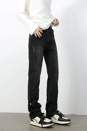 Dark denim jeans with asymmetric seams and button details.