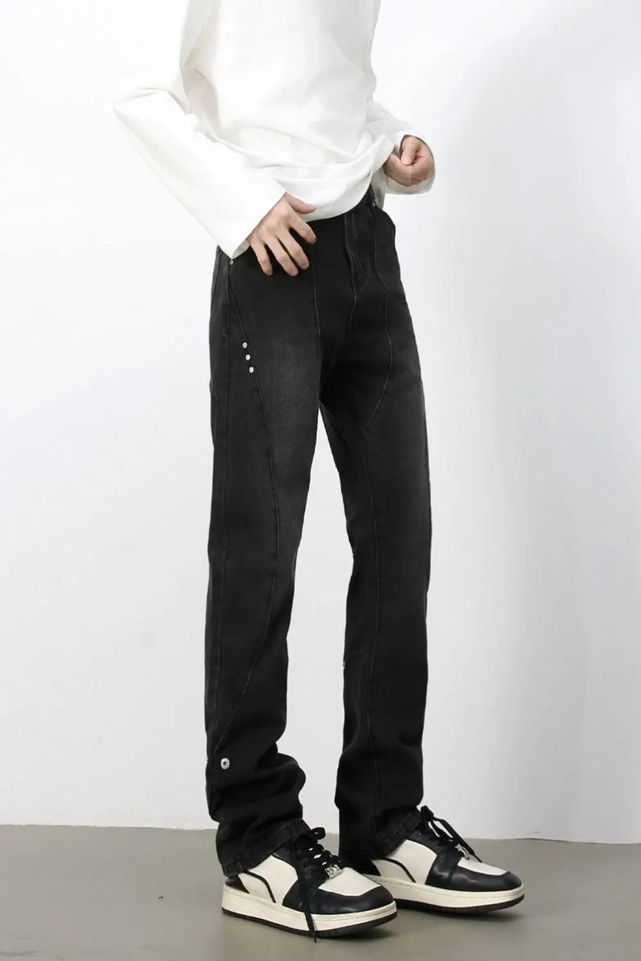 Dark denim jeans with asymmetric seams and button details.