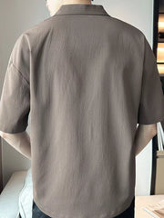 Taupe cotton polo shirt with textured fabric and short sleeves.