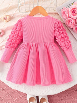 Pink ribbed baby dress with bubble texture sleeves and a gathered skirt.
