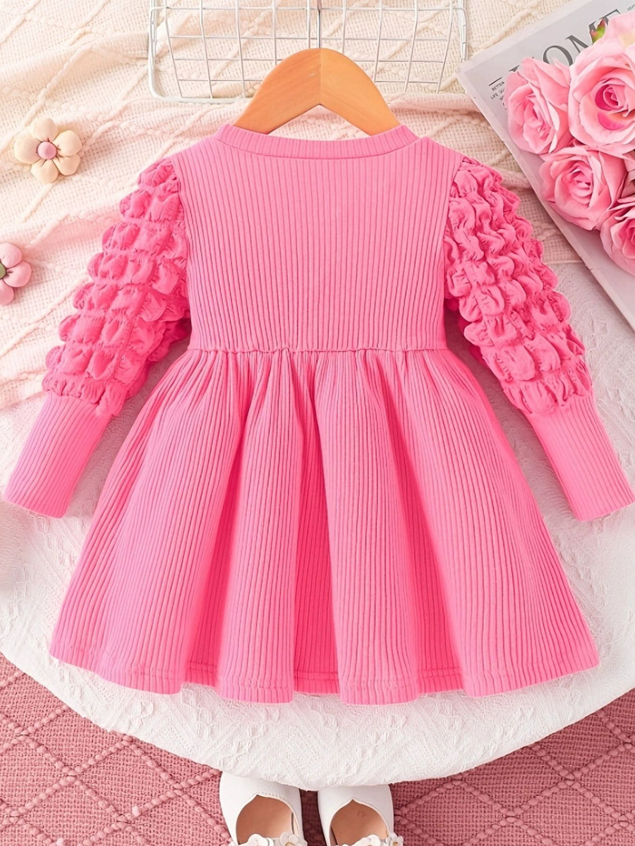Pink ribbed baby dress with bubble texture sleeves and a gathered skirt.