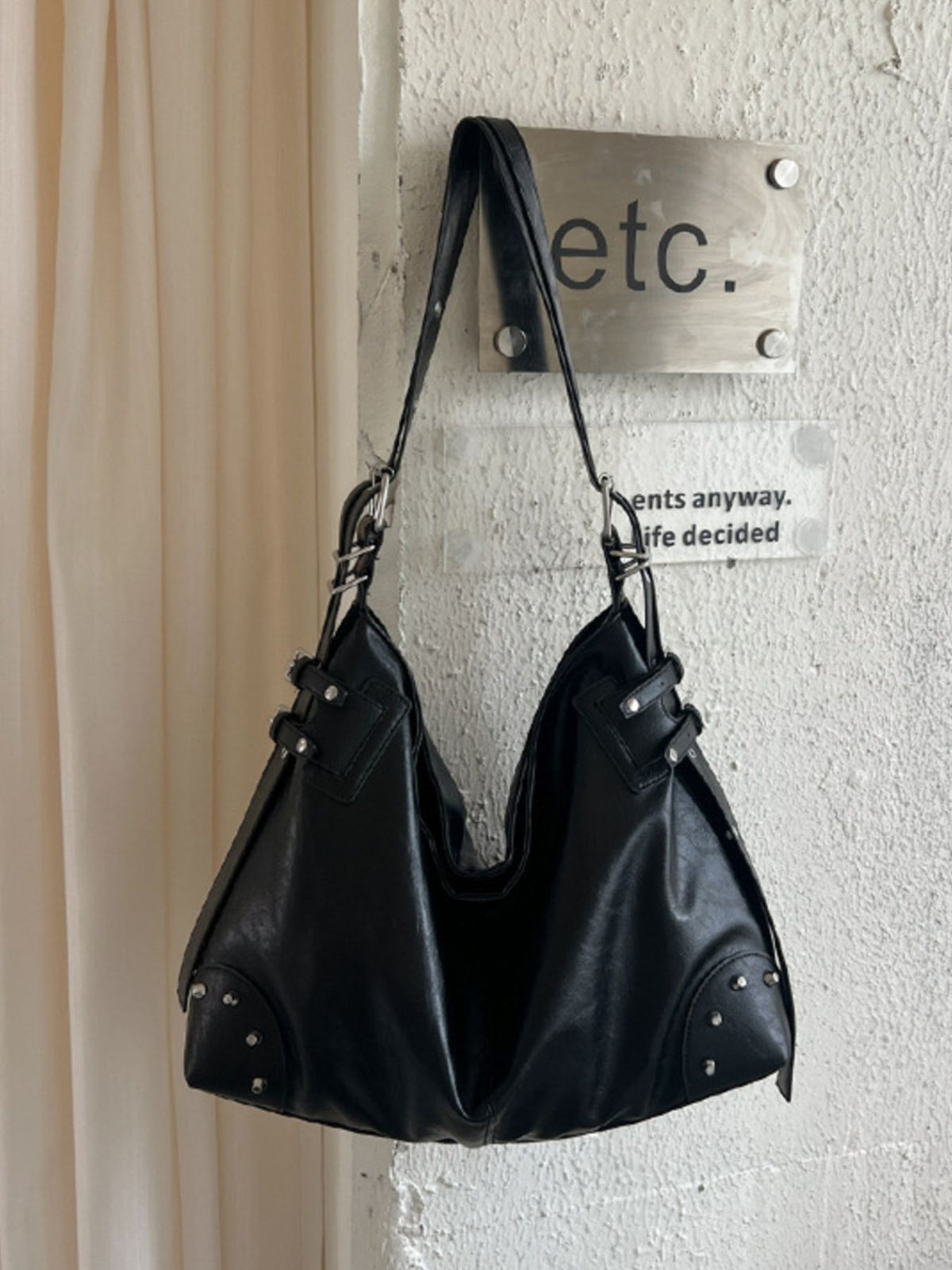 handbag in black featuring rivet decor and relaxed fit