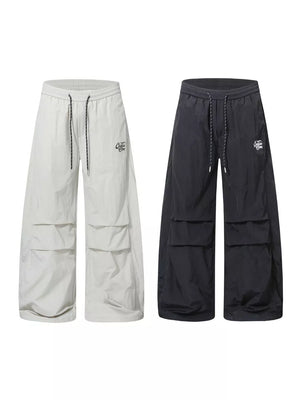 Men's wide-leg cargo pants in cream white and black with drawstring waist and multiple pockets.
