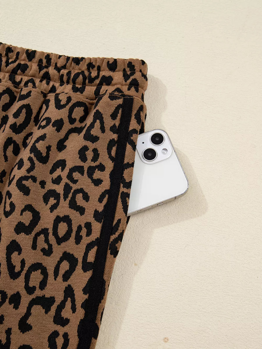 Leopard print joggers with drawstring waist and side stripe detail, showing a phone in the pocket.