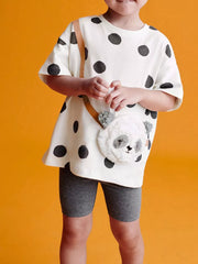 White polka dot t-shirt with plush panda crossbody bag and grey biker shorts.