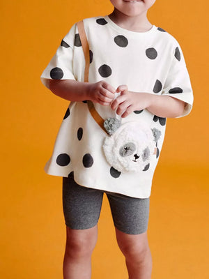 White polka dot t-shirt with plush panda crossbody bag and grey biker shorts.