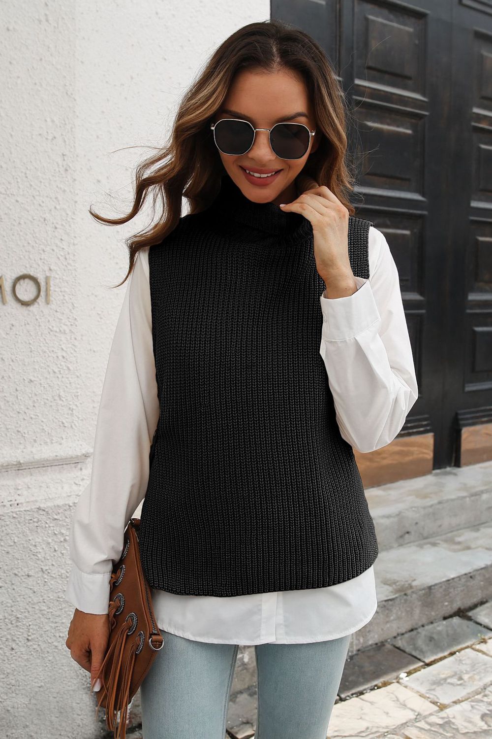 Black ribbed knit turtleneck vest with side buttons, acrylic, worn over a white shirt.