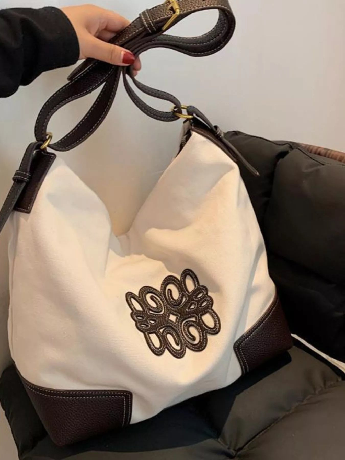 White canvas tote bag with dark brown leather trim and embroidered logo