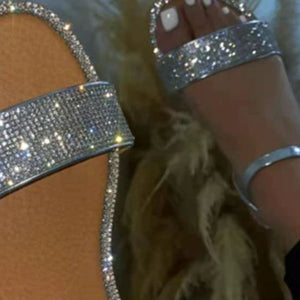 Silver rhinestone-embellished flat ankle sandals with a single strap across the foot.