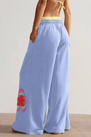 Light blue cotton maternity pants with wide legs and a floral applique detail.