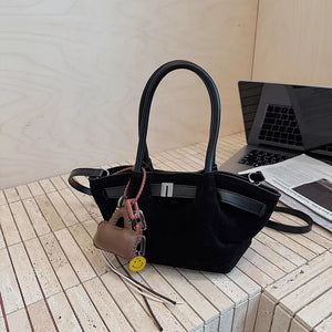 Black suede and leather mini tote bag with charms and silver buckle detail.