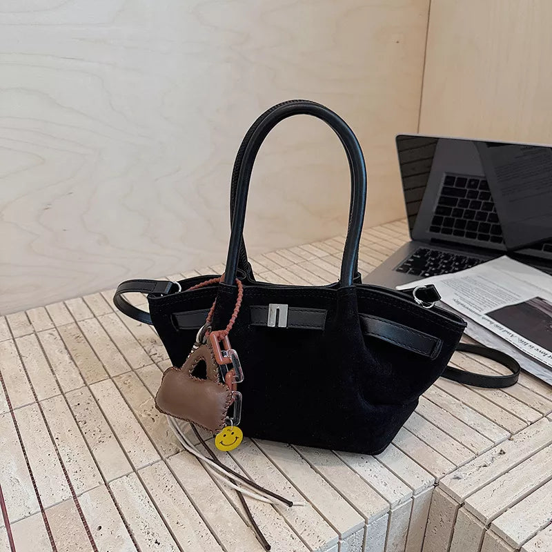 Black suede and leather mini tote bag with charms and silver buckle detail.