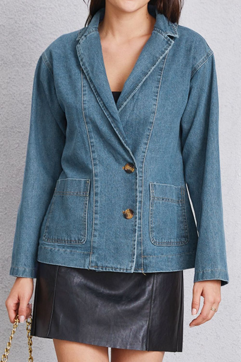 Medium denim blazer with tailored seam detailing, two buttons, and flap pockets.