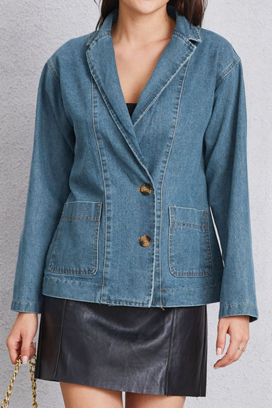 Medium denim blazer with tailored seam detailing, two buttons, and flap pockets.