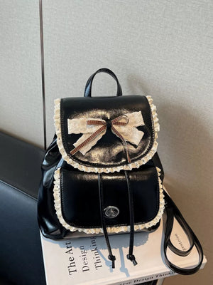 Black mini backpack with lace trim and a bow, featuring a drawstring closure and front pocket.