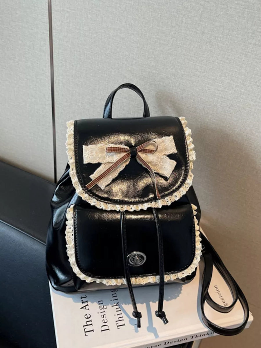 Black mini backpack with lace trim and a bow, featuring a drawstring closure and front pocket.