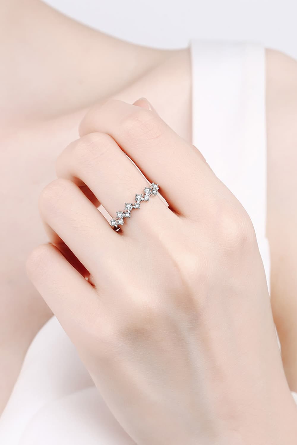 Silver zigzag diamond cluster ring with small stones on a hand.