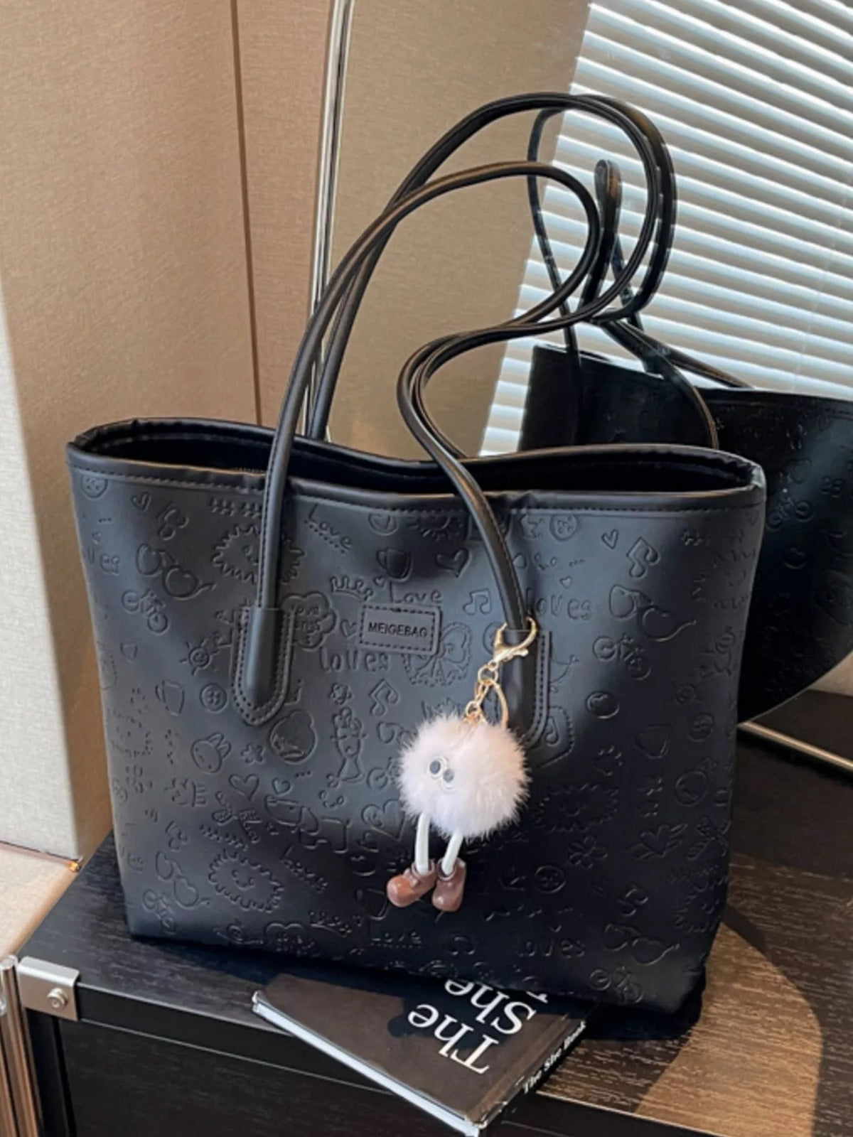 Black embossed PU leather tote bag with cute charm and playful pattern.