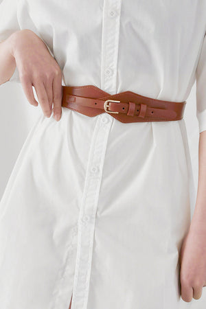 Brown leather geometric belt with gold buckle cinching a white dress