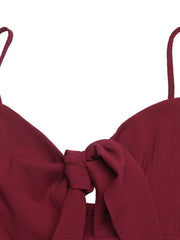 Burgundy bow-knot detail spaghetti strap romper with textured fabric.
