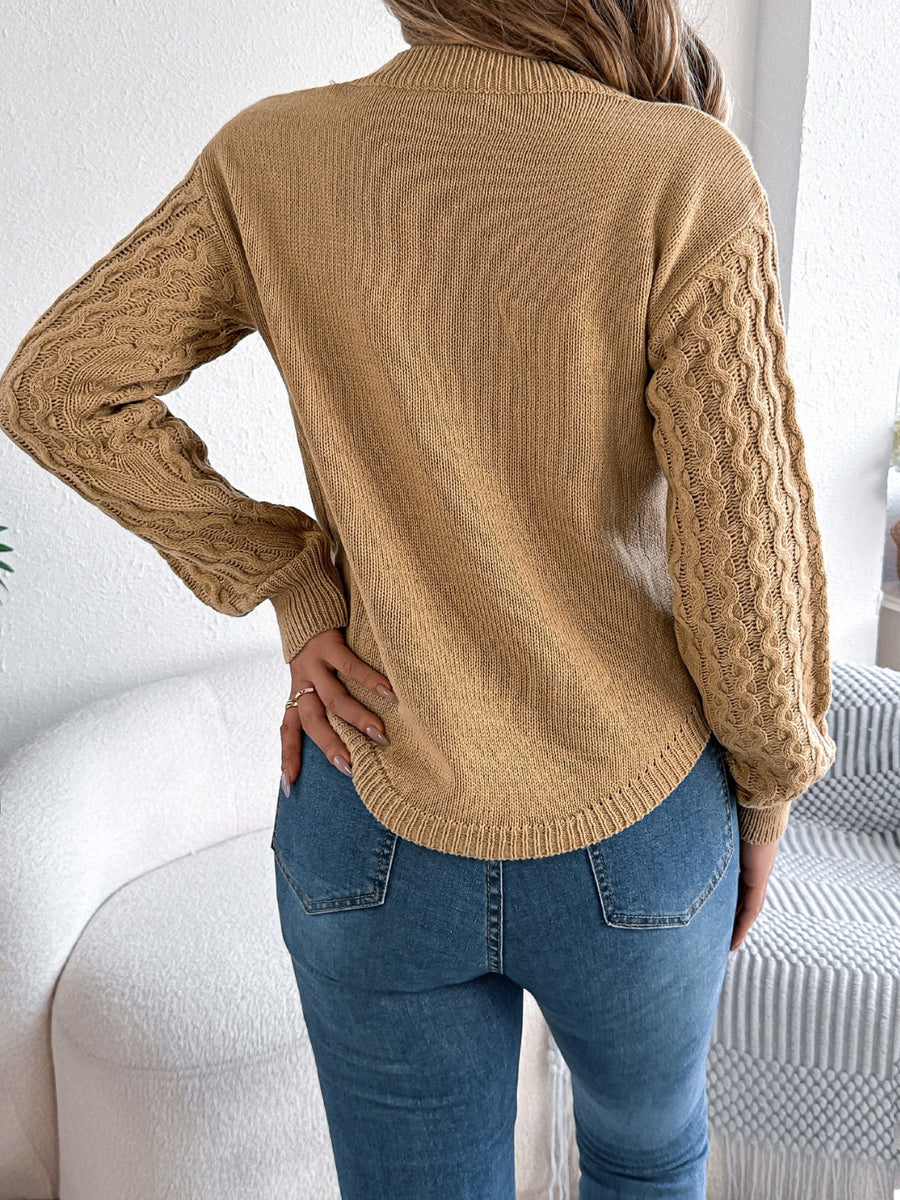 Camel knit sweater with textured cable sleeves and asymmetric hem.
